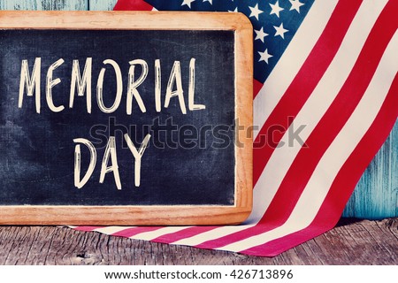 the text memorial day written in a chalkboard and a flag of the United States, on a rustic wooden background