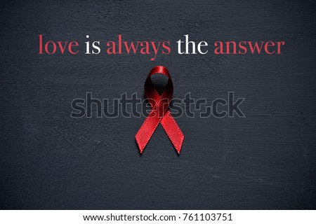 a red ribbon for the fight against AIDS and the text love is always the answer on a dark gray surface