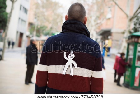 young man in the street with a paper man in his back as a prank for the dia de los inocentes, the innocents day, a feast held in spain, hispanic america and philippines equivalent to april fools day