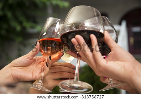 Group of unrecognizable people celebrating while holding wine glasses and toasting.