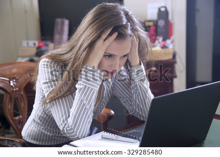 Worried businesswoman using laptop in her office and has headache because of problems at work.