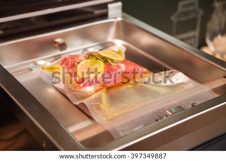 Beefsteak in olive oil with rosemary and lemon in vacuumed package. Sous-vide. Using vacuum seal machine for meal packing.
