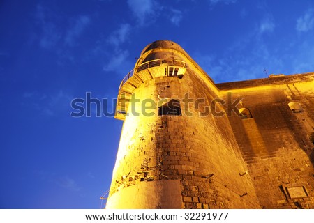close up of part of an ancient fortification on the maltese islands illuminated by a powerful light taken at twilight