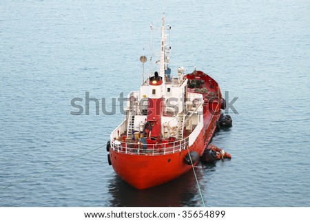 a red tug boat moored in a harbor
