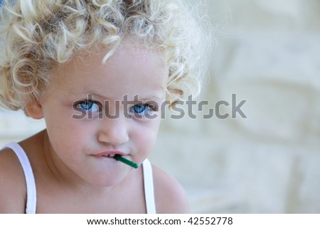 a young caucasian child with a dangerous small object in her mouth