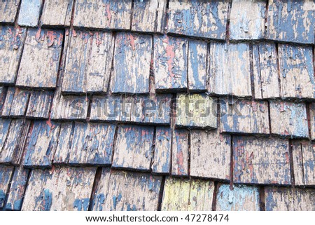 old wooden slated roof top with peeling paint and cracks in the wood