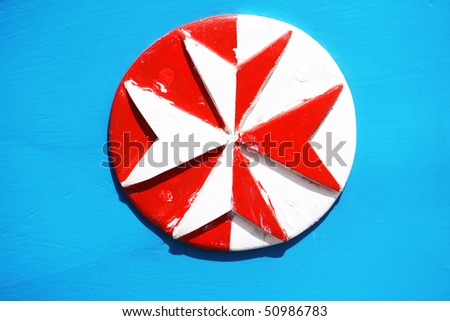 wooden eight pointed cross painted in white and red on a bright blue background
