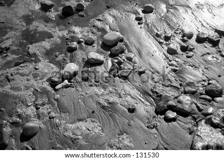 Glistening wet rocks, mud, sand, and water (black and white)