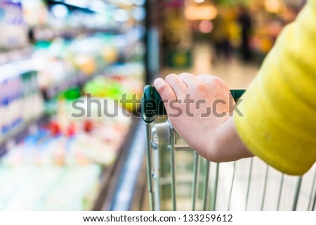 Closeup of female shopper with trolley at supermarket