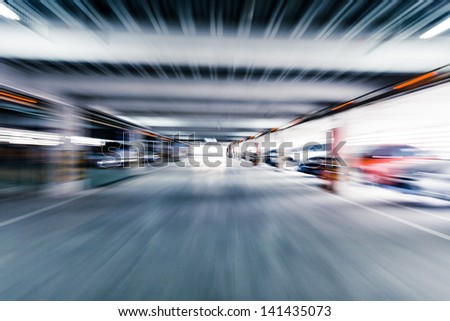 Parking garage, interior with a few parked cars.Motion blur
