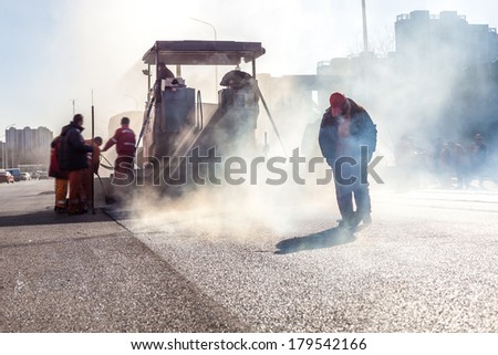 Workers making asphalt with shovels at road construction