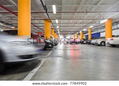 The shined underground garage with the moving cars and parked cars