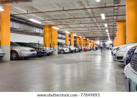 The shined underground garage with the moving cars and parked cars