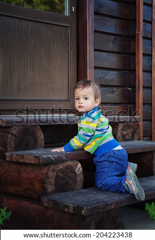 cute little child climbs the wooden stairs to the house. small depth of field (DOF)