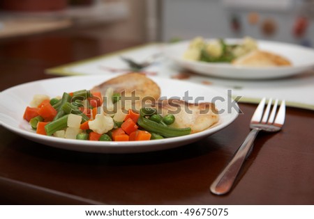 Plate of grilled vegetables with fired fish - served table. Shallow focus depth on front plate