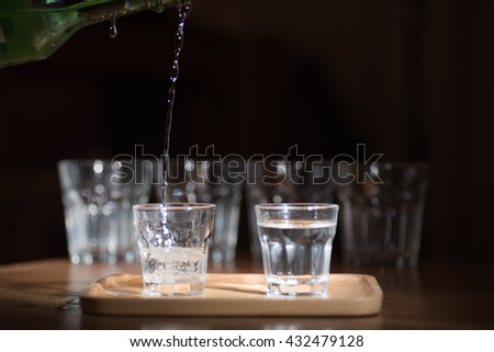 soft focus image for sake.\
Sake -flavored soft sweet scent was poured from a bottle into a small glass on darken background .Ideal for celebrations.