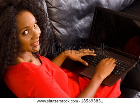 a beautiful african american woman at home with her laptop computer.
