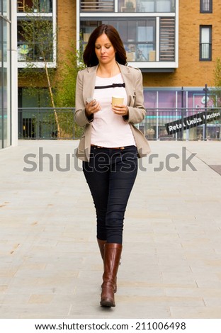 young woman sending text and drinking coffee while on the go.