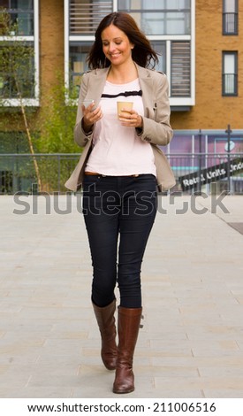young woman walking with coffee and phone.