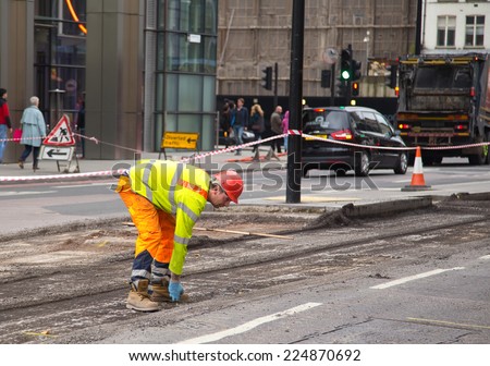 LONDON - OCTOBER 18TH: Unidentified workman resurfacing a road on October 18th, 2014 in London, England, UK. The city council carry\'s out annual road condition surveys