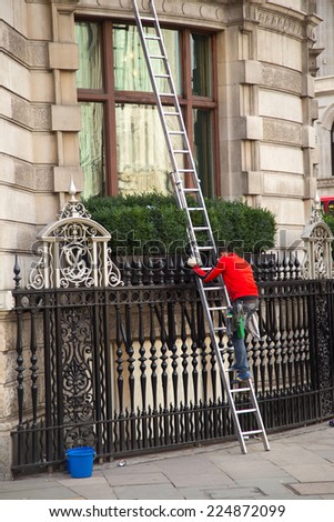 LONDON - OCTOBER 18TH: Unidentified man cleaning windows on October 18th, 2014 in London, England, uk. Cleaners need to follow strict safety guidelines.