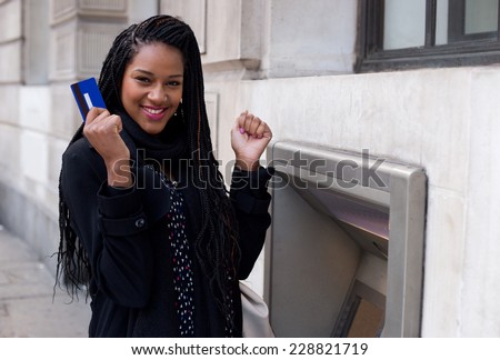 a young woman looking happy at the cash machine.