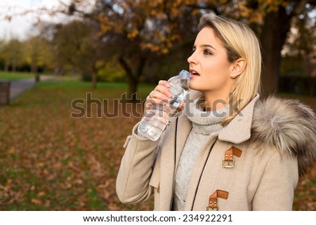 young woman drinking water in a park