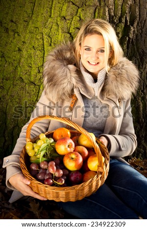 young woman holding a basket of fruit in a park