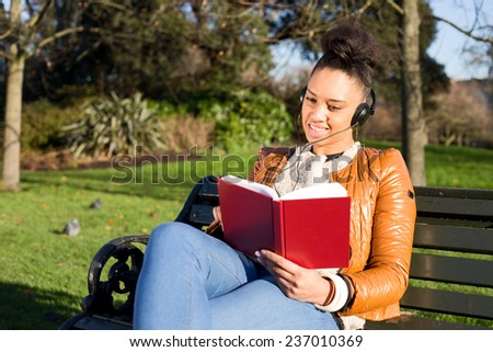 young woman reading a book and listening to music.