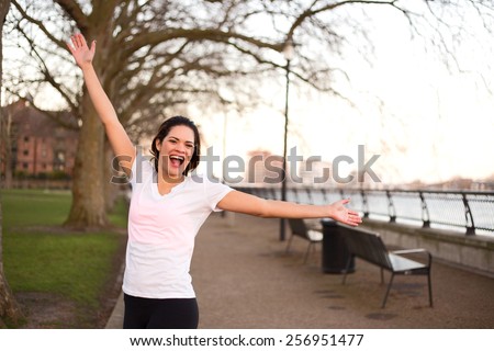 happy woman outdoors celebrating a fitness goal.