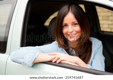 happy young woman looking out of her car window.