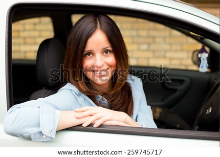 happy young woman sitting in a car looking out of the window.