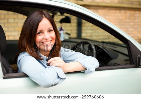young woman looking out of her car window holding her keys