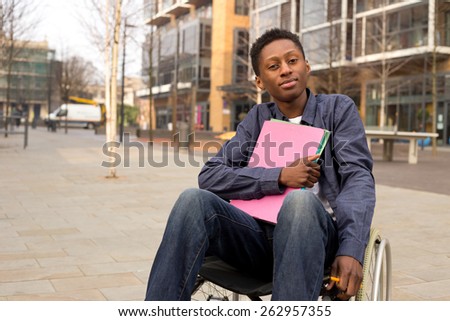 young disabled student sitting in a wheelchair  holding folders