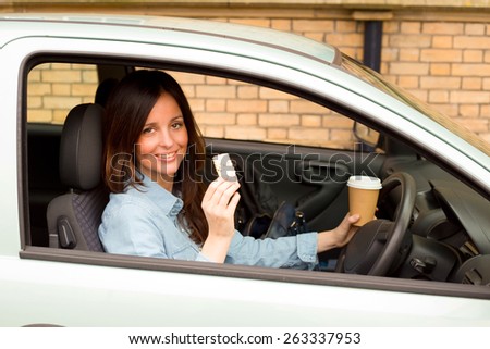 young woman enjoying a healthy snack and a cup of coffee in her car.