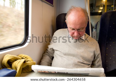 old man reading the newspaper on the train