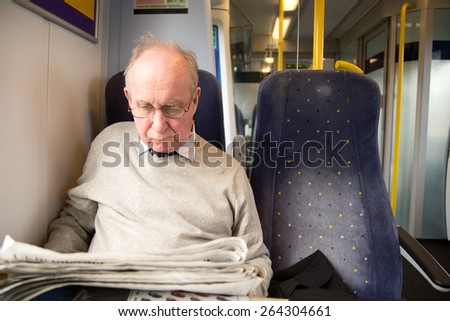 old man reading the newspaper on the train
