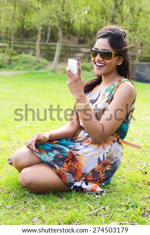 happy indian woman checking her text messages in the park