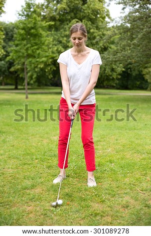 young woman teeing off on the golf course