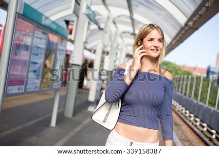 young woman on the train platform using her phone