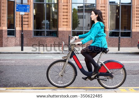 young woman riding a hire bike in the street