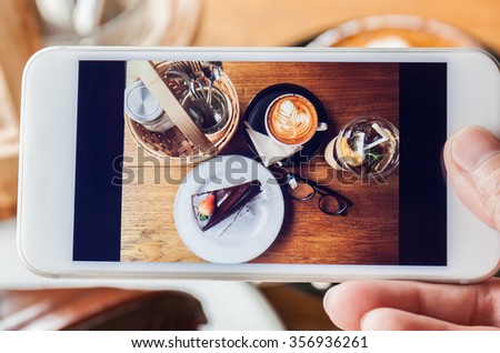 Photo of chocolate cake, cappucino, eyeglass, seasoning and peach tea through smartphone
