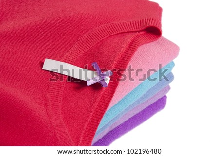 Pile of multicolored knitted clothes with blank label macro on white