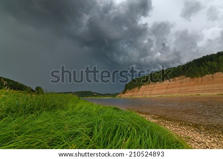 The river with the cool high coast during the coming nearer storm. Drama natural landscape.