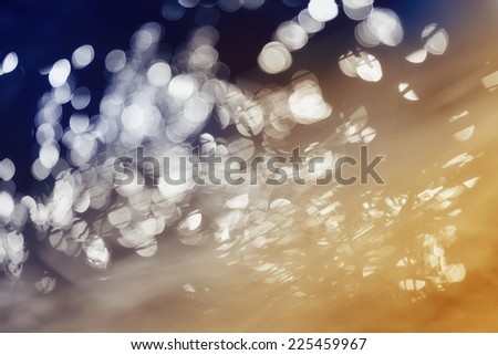 Tinted in shades gold and blue  abstract sparkling background. The bright patches of light removed in  movement and blurred.