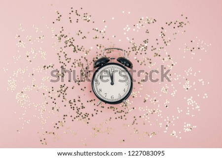 New Year Christmas Top view flat lay black alarm clock twelve covered golden stars confetti copy space millennial pink color paper background minimal style Template feminine blog social media postcard