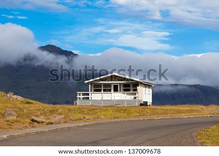 White Wooden House and asphalt road in East Iceland. Horizontal shot