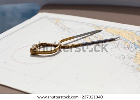 Pair of compasses for navigation on a sea map with low depth of field
