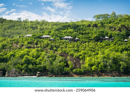 View of Seychelles coastline with houses in the forest. Horizontal shot