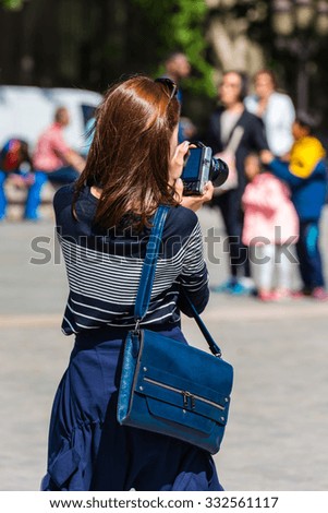 FRANCE, PARIS - JUNE 01: Back side of a young woman taking a photo with her camera in Paris on June 01, 2015